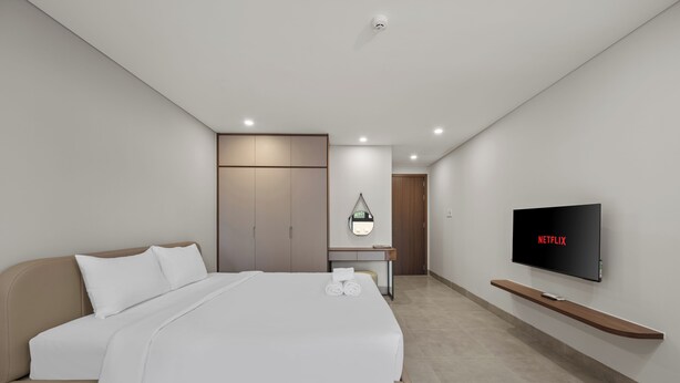 Una habitación de hotel moderna con cama, televisor, escritorio y armario.