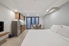 A modern hotel room with a bed, a kitchenette, a TV, and a large window. - Hampton Danang Central Apartment (Son Tra)