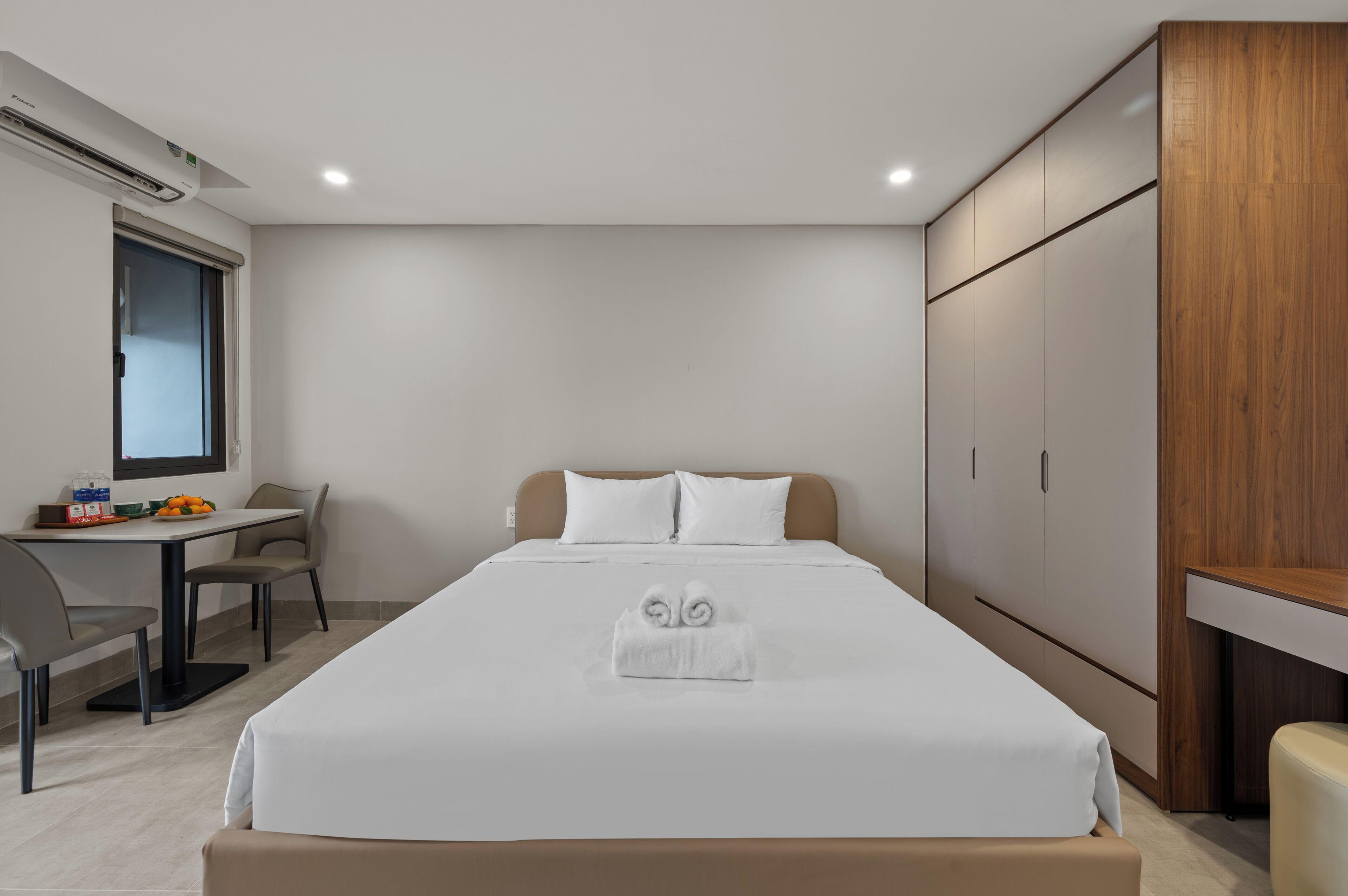 A hotel room with a bed, a desk, a chair, and a wardrobe.