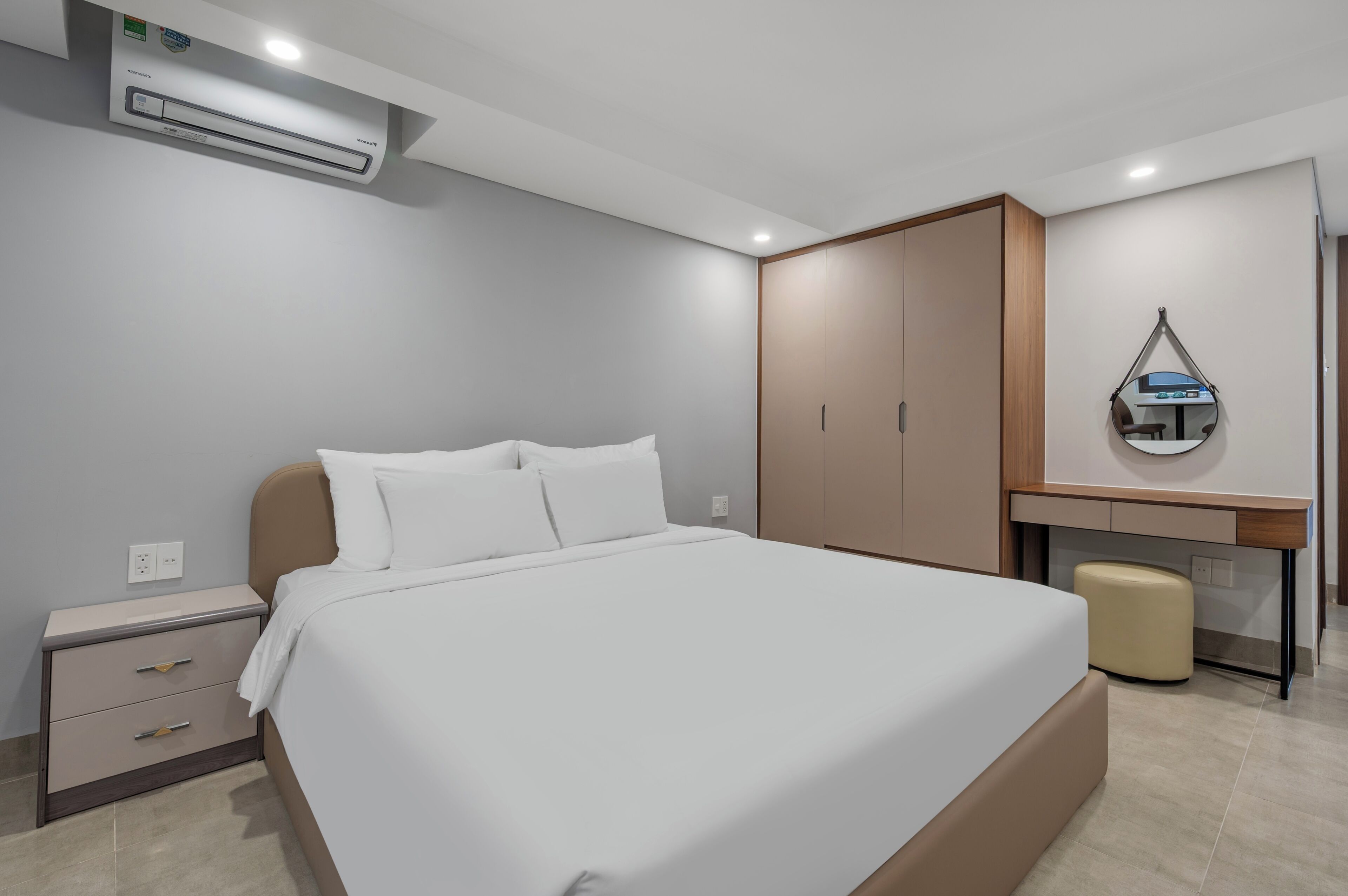 A modern bedroom with a bed, bedside tables, a wardrobe, and an air conditioning unit.