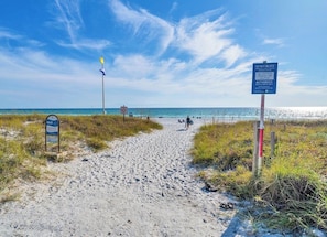 A sandy beach path with signs, a flag, and the ocean in the background. - Beautiful 2 bedroom/2 bath condo in Santa Rosa Beach (Santa Rosa Beach)