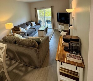 A living room with a sofa, a coffee table, a TV, and a coffee machine. - Beautiful 2 bedroom/2 bath condo in Santa Rosa Beach (Santa Rosa Beach)