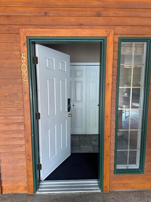 Une maison en bois avec une porte blanche, une fenêtre à cadre vert et une boîte aux lettres.