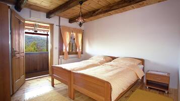 A wooden bedroom with a bed, a nightstand, and a window with curtains.
