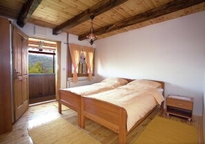 Ein Schlafzimmer aus Holz mit einem Bett, einem Nachttisch und einem Fenster mit Vorhängen.