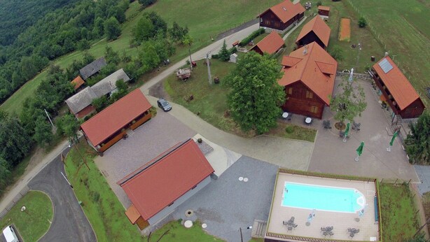 En lantlig fastighet med flera byggnader, en swimmingpool och ett grönskande område runt omkring.