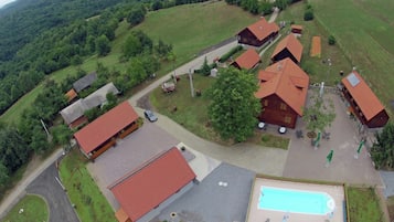 A rural property with multiple buildings, a swimming pool, and a surrounding green landscape.