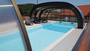 En pool med ett överbyggt område, solstolar och ett trädäck.