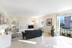 Ein modernes Wohnzimmer mit Sofa, Fernseher und einem Balkon mit Blick auf einen Turm.