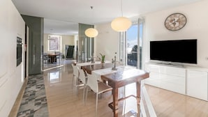 Een moderne keuken met een eethoek, grote ramen en een flatscreen televisie.