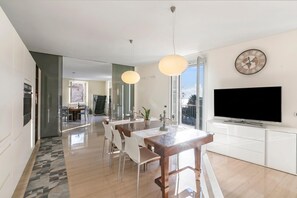 Eine moderne Küche mit Essbereich, großen Fenstern und einem Flachbildfernseher.