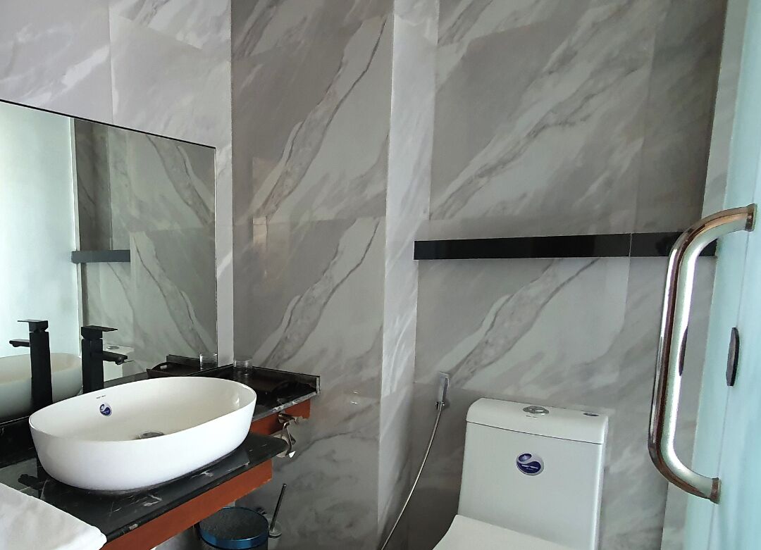 Un baño con un lavamanos blanco, encimera negra y un espejo.