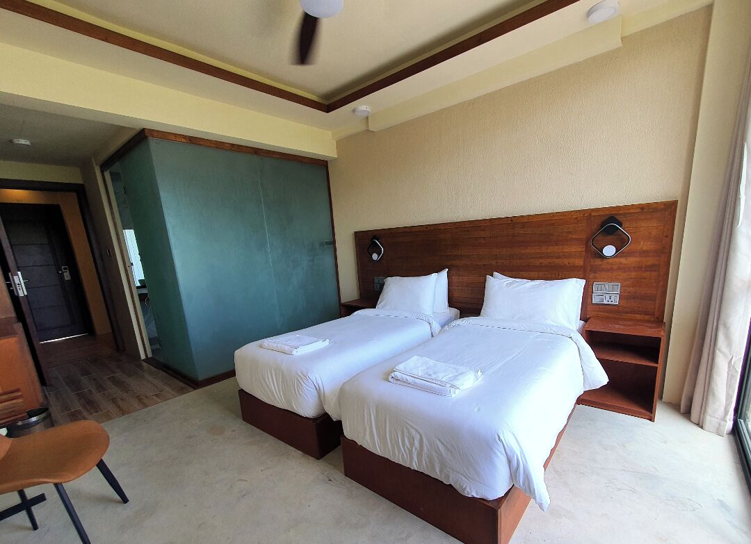 A hotel room with two beds, a wooden headboard, a desk, and a chair.