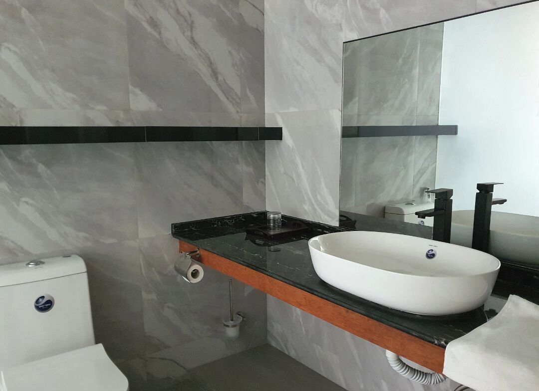 A modern bathroom with a marble wall, a white sink, and a black faucet.