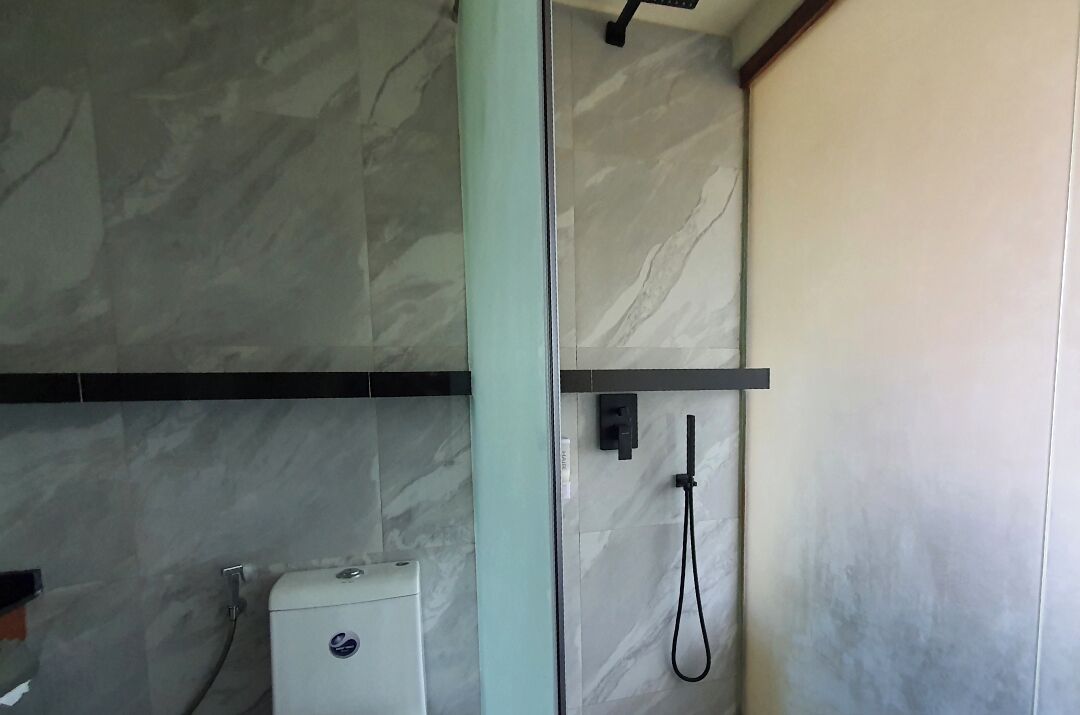 Un baño moderno con cabina de ducha de vidrio, azulejos de mármol y un inodoro a la vista.