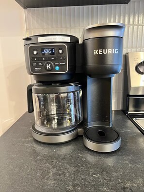 Eine Kaffeemaschine von Keurig mit Glasbehälter und einer Kaffeekanne auf einer Küchenarbeitsplatte.