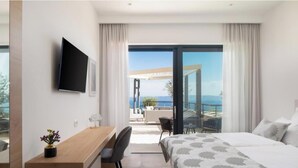 Habitación de hotel con cama, escritorio, silla, televisor y balcón con vistas.