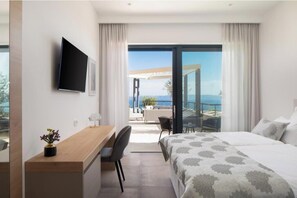 Ein Hotelzimmer mit Bett, Schreibtisch, Stuhl, Fernseher und einem Balkon mit Aussicht.