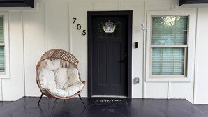 A black door with the number 705, a wicker chair, and a welcome mat.