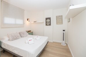 A neatly made bed with a white bedspread and two pillows, a small bedside table with a book, a wall-mounted light, and a sign with a coffee theme. - GuestReady - Fuentebravia with terrace and pool (El Puerto de Santa María)
