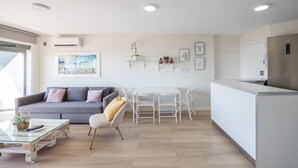 Un espacio habitable moderno con sofá, mesa de centro, mesa de comedor, sillas y una zona de cocina.