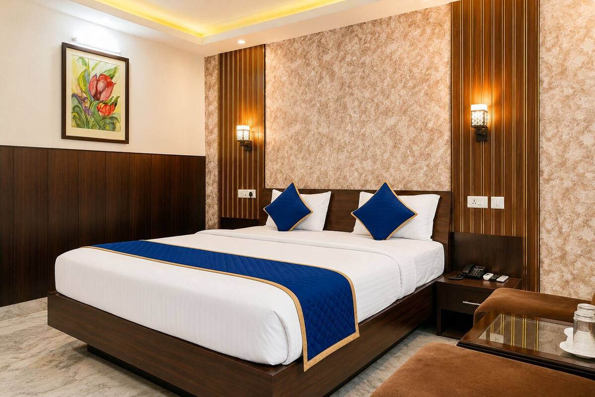 Quarto de hotel com cama grande, mesa de cabeceira, escrivaninha e um quadro na parede.