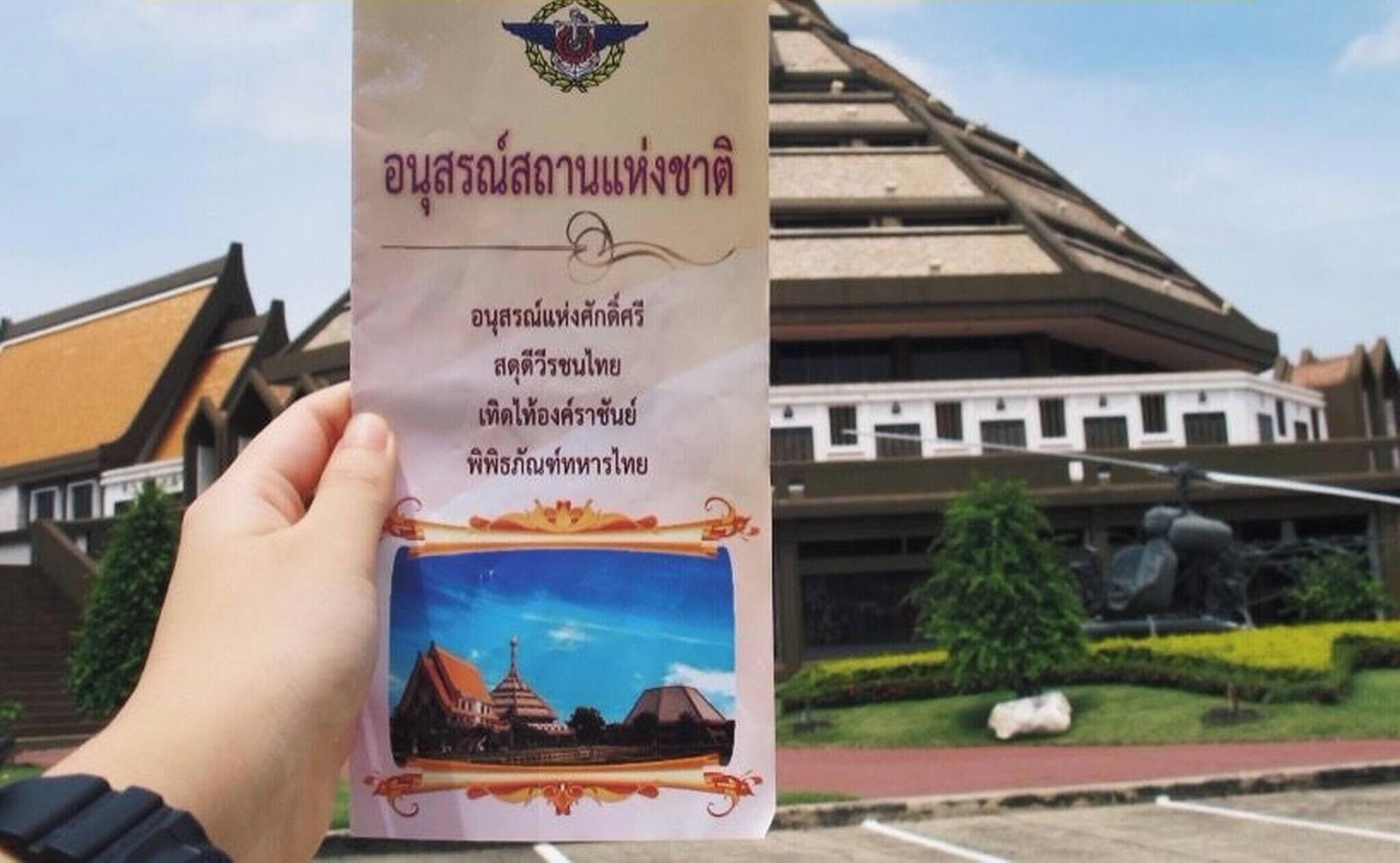 A person holding a brochure with a temple and a car in the background.