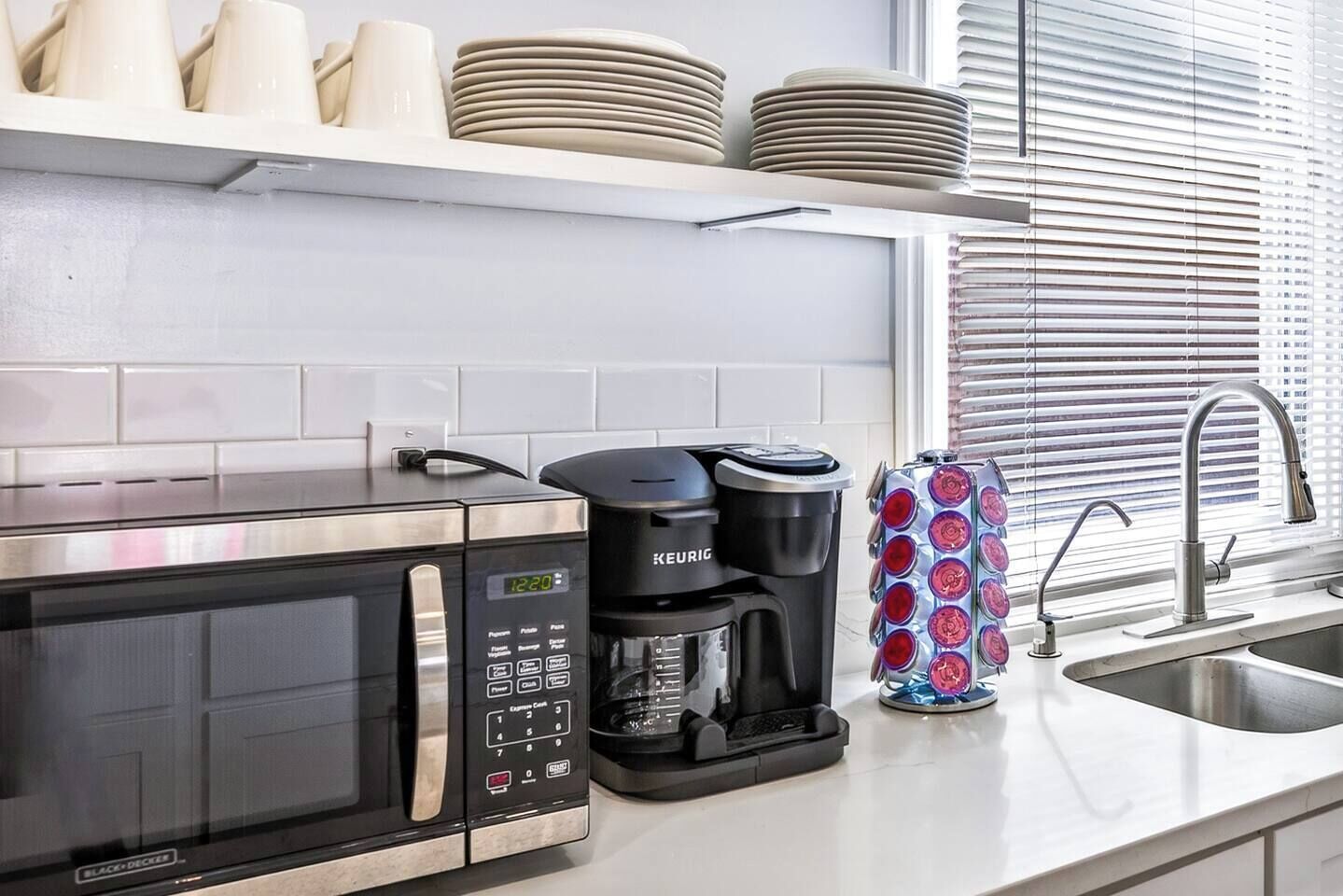A kitchen with a microwave, coffee maker, and a sink.