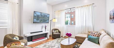 A modern living room with a flat-screen TV, a fireplace, a sofa, and a coffee table.