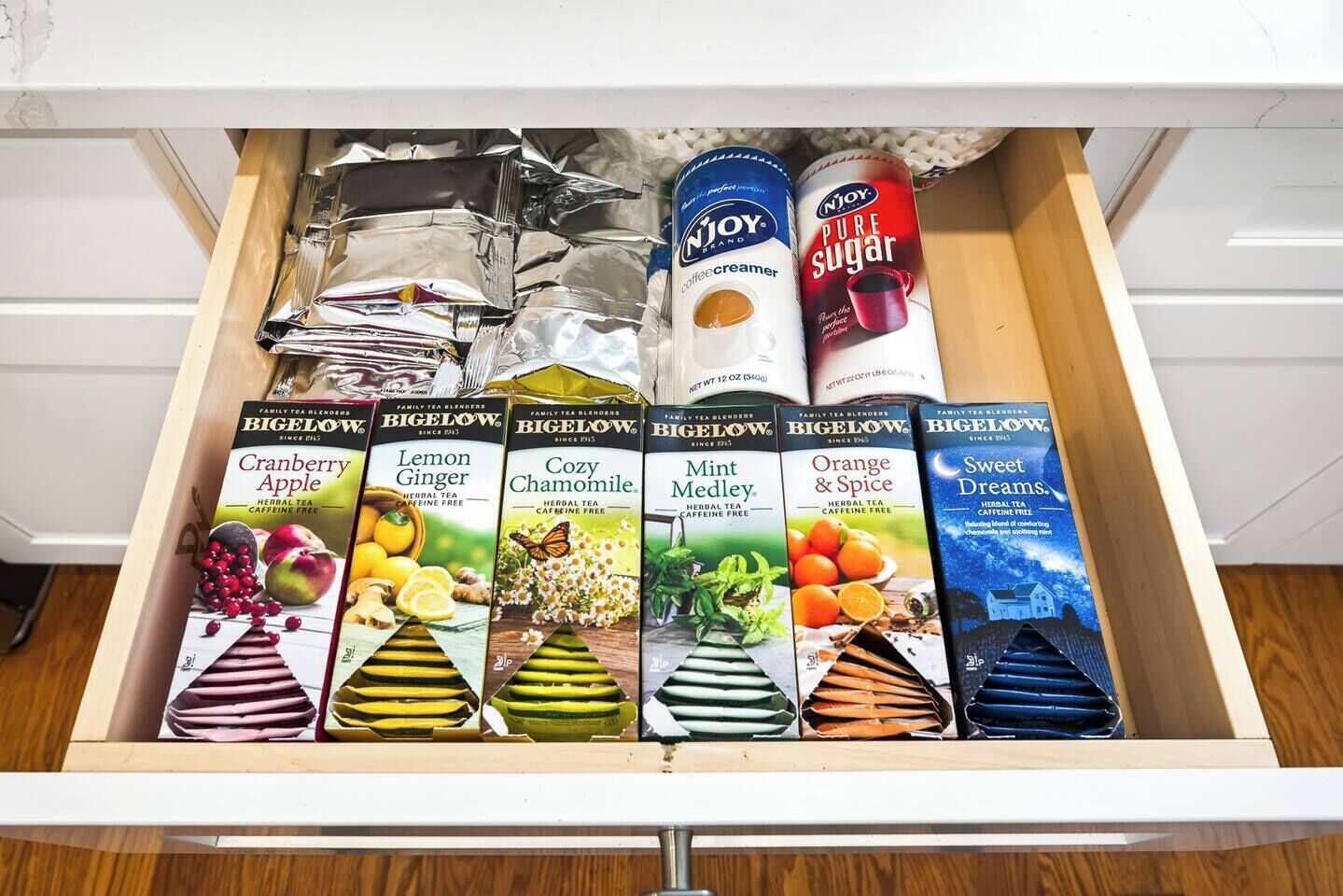 A drawer with various tea blends, a coffee creamer, and a sugar container.