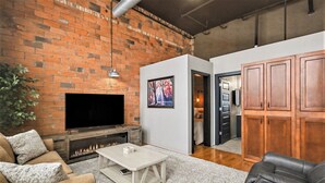 Ein Wohnzimmer mit Kamin, Fernseher, einer Couch und einem Essbereich mit Holzschränken.