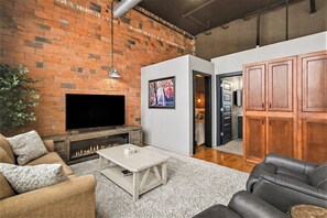Ein Wohnzimmer mit Kamin, Fernseher, einer Couch und einem Essbereich mit Holzschränken.