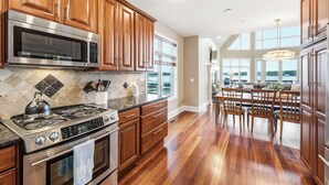 A kitchen with wooden cabinets, stainless steel appliances, a tiled backsplash, and a dining area with a chandelier. - Lakeview on Magician- lakefront luxury (Dowagiac)