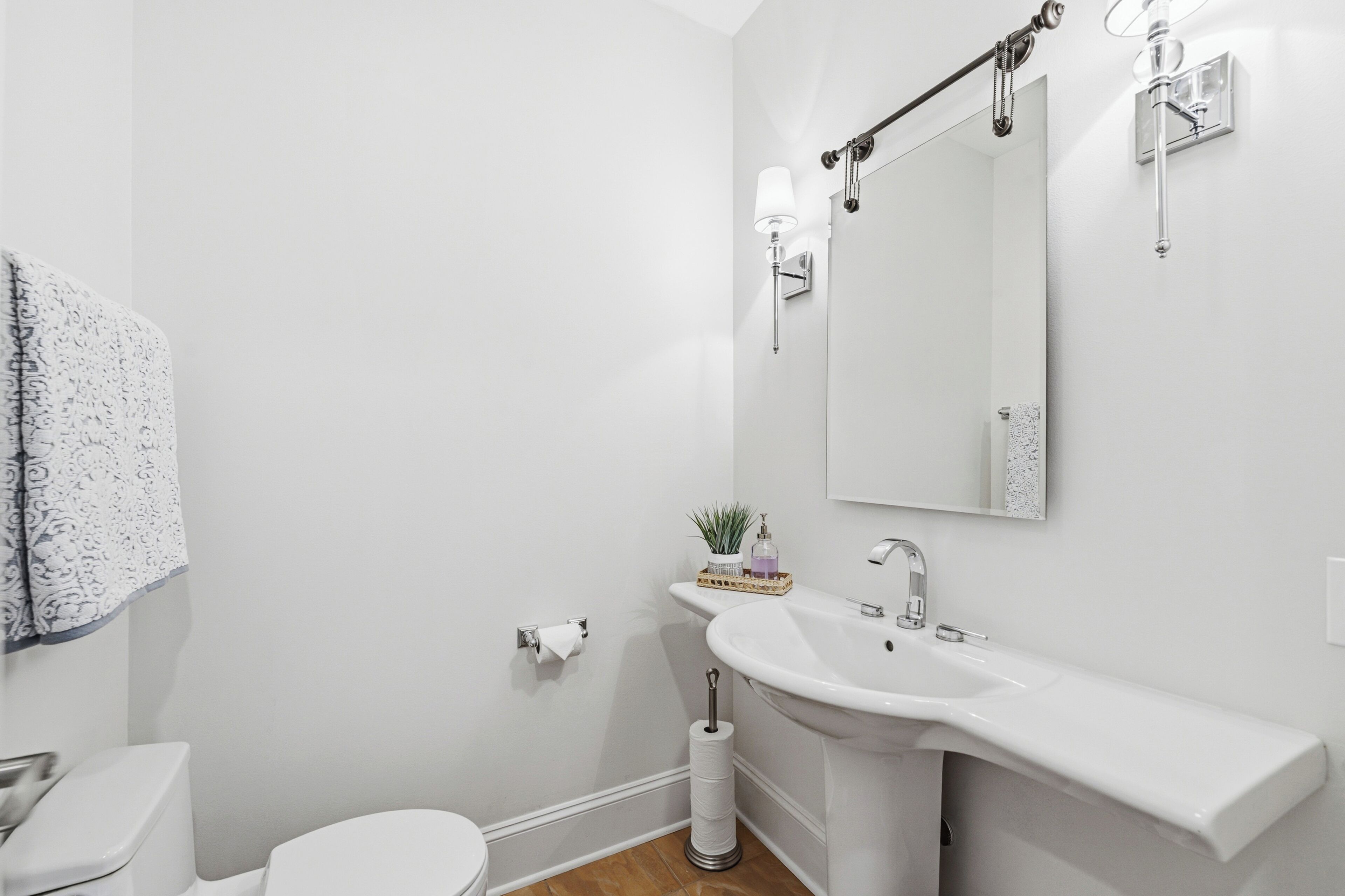 Een badkamer met een wit wastafel, toilet en een handdoek aan de muur.