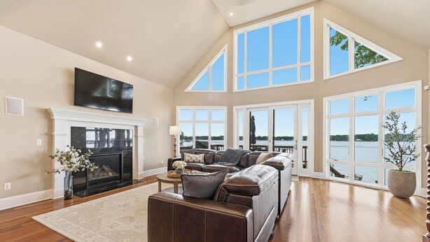 A spacious living room with a fireplace, large windows, and a view of the water. - Lakeview on Magician- lakefront luxury (Dowagiac)