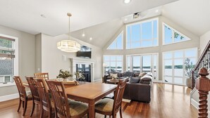 A spacious living area with a dining table, chairs, a sofa, and a staircase. - Lakeview on Magician- lakefront luxury (Dowagiac)