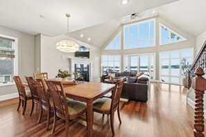 A spacious living area with a dining table, chairs, a sofa, and a staircase.