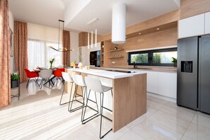 Eine moderne Küche mit einer zentralen Kochinsel, Barhocker und einem Edelstahl-Kühlschrank.