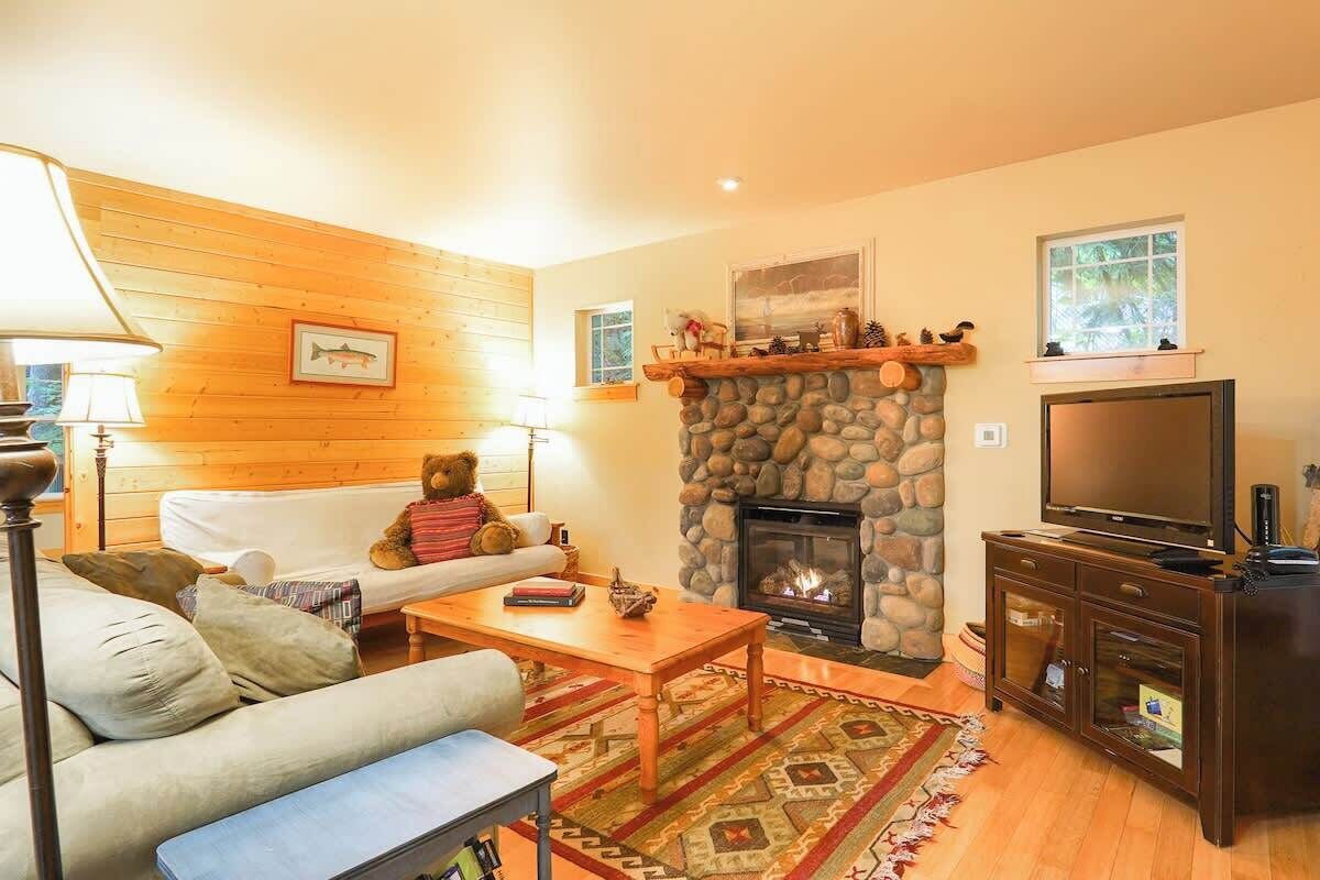 Una sala de estar acogedora con chimenea de piedra, televisor y sofá.