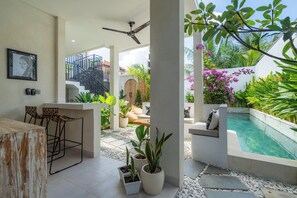 Um pátio moderno ao ar livre com piscina, área de estar e plantas em vasos.