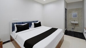 A hotel room with a bed, a bedside table, a wall-mounted TV, and a bathroom with a sink and mirror. - Deluxe Room Adithya Stay (Hyderabad)