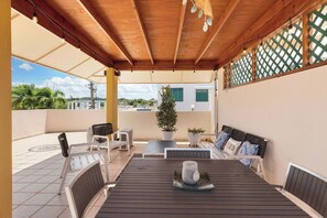 A covered outdoor seating area with a table, chairs, and potted plants. - La Villita de Panchi | Near Poblado, Pool & Tennis (Cabo Rojo)