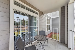 A balcony with a table and chairs, large windows, and a view of a park. - Family & Pet Friendly Escape Near Disney (Kissimmee)