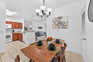 A modern kitchen with wooden cabinets, a dining table set with black bowls, and a chandelier. - Family & Pet Friendly Escape Near Disney (Kissimmee)
