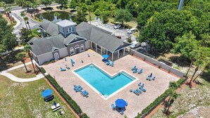 Eine Vogelperspektive zeigt ein Resort mit Schwimmbad, Liegestühlen und einer überdachten Terrassenanlage.