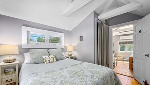 Een slaapkamer met een bed, twee nachtkastjes, een raam en een deur naar een balkon.