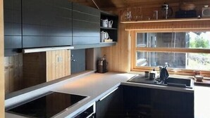Eine moderne Küche mit Holzausstattung, einem eingebauten Herd und einem Fenster mit Ausblick.