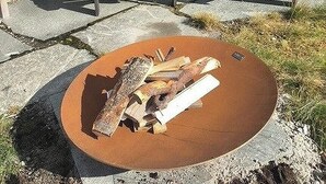 Ein rustikaler Außenbereich mit Adirondack-Stühlen und einem Feuerkorb.