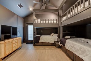 Una habitación con literas, televisión, cómoda de madera y ventilador de techo.