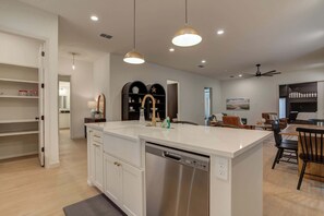 Cocina moderna con una isla central, iluminación colgante y lavavajillas.